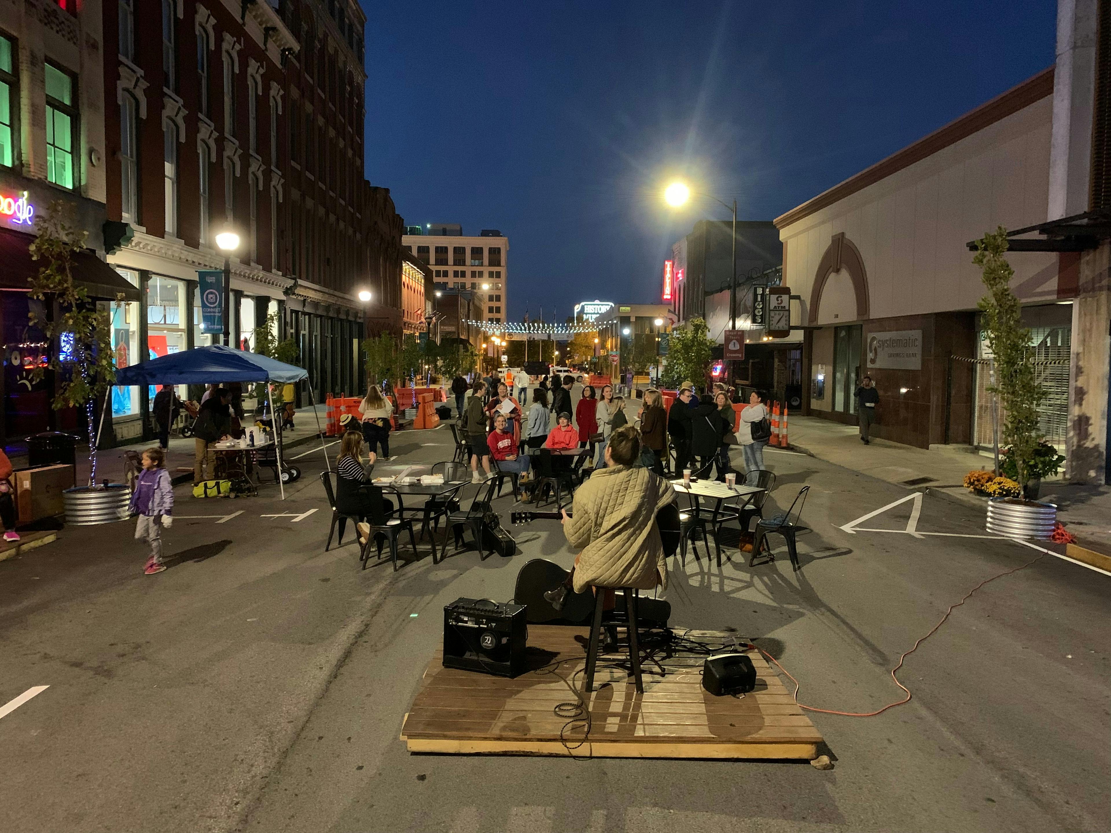 Image of a performer playing guitar at night in the middle of South Avenue.